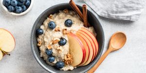 oatmeal porridge with apple, cinnamon and blueberries in bowl on grey concrete background, top view healthy breakfast food for autumn comfort food