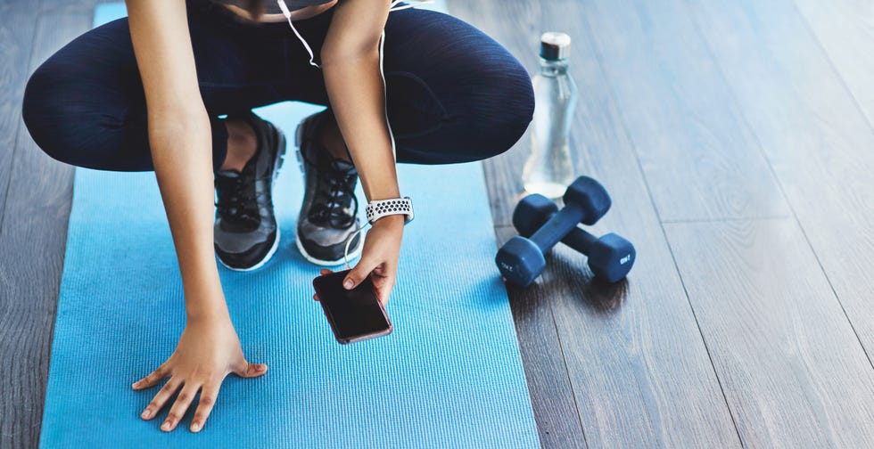 closeup shot of a sporty woman using a cellphone while exercising in a studio