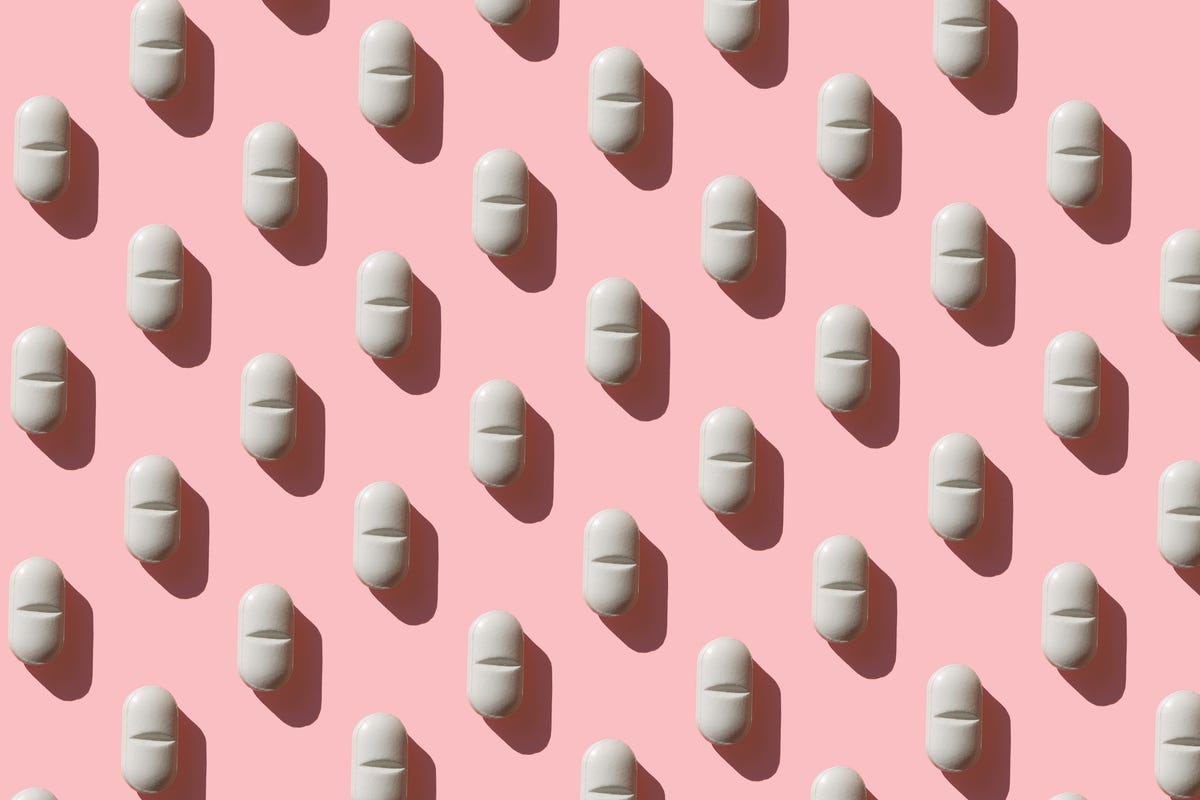 rows of white tablets on a pink background
