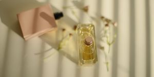 two perfume bottles and some widlfowers on a white background in a beautiful sunlight coming through blinds