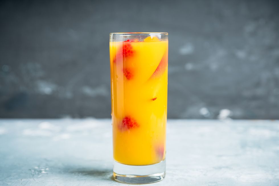 fresh peach beverage with red ripe raspberry on the rustic background selective focus