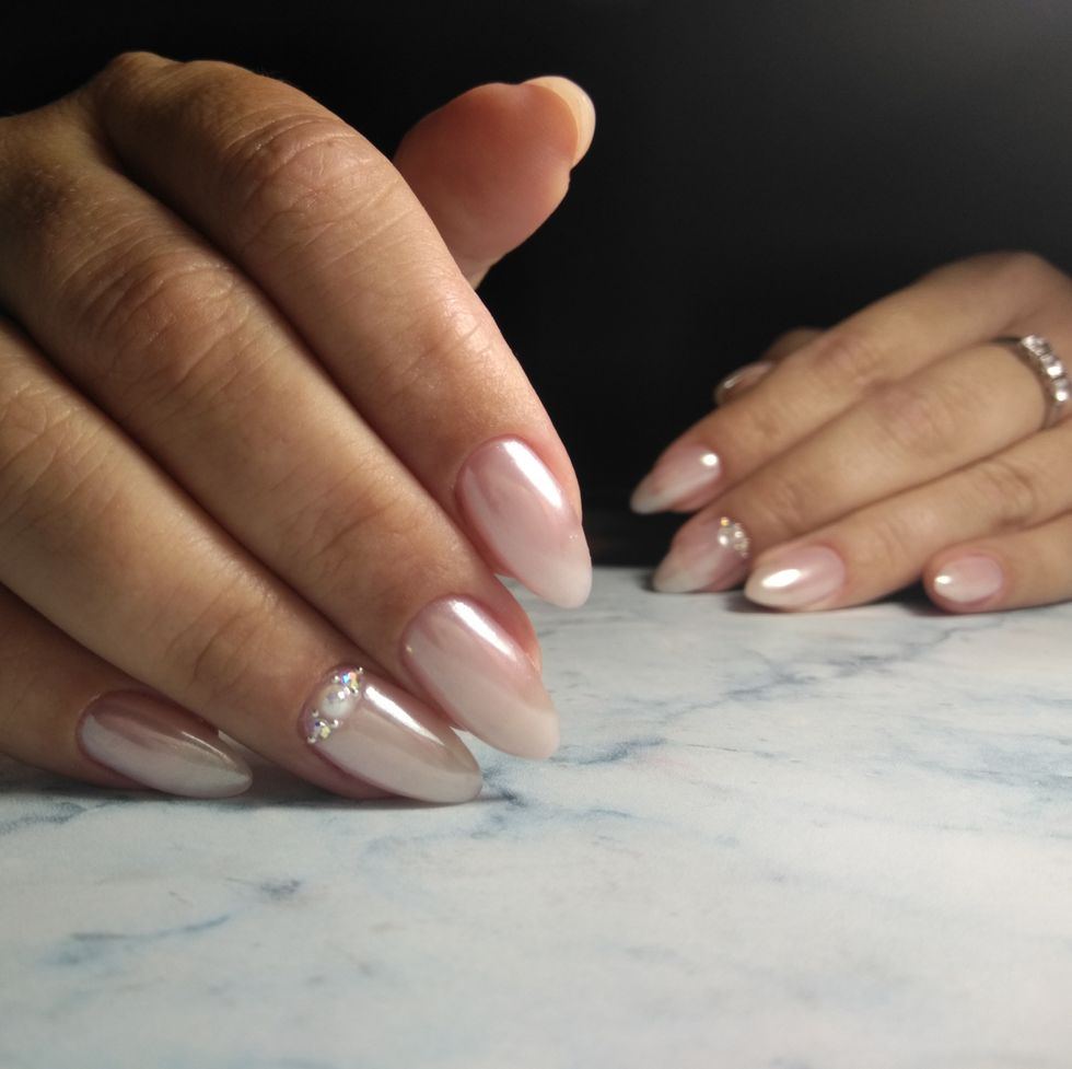 manicure with shiny coating and lined with rhinestones pearl design with pink tint