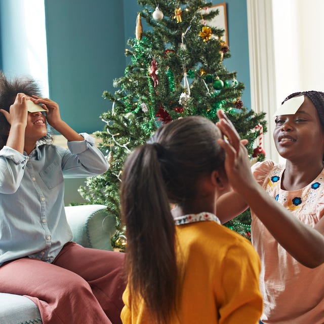 sisters sticking adhesive notes on forehead while sitting in living room at home during christmas