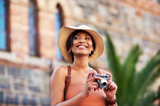 shot of an attractive young woman taking pictures with a camera while exploring in a  foreign city