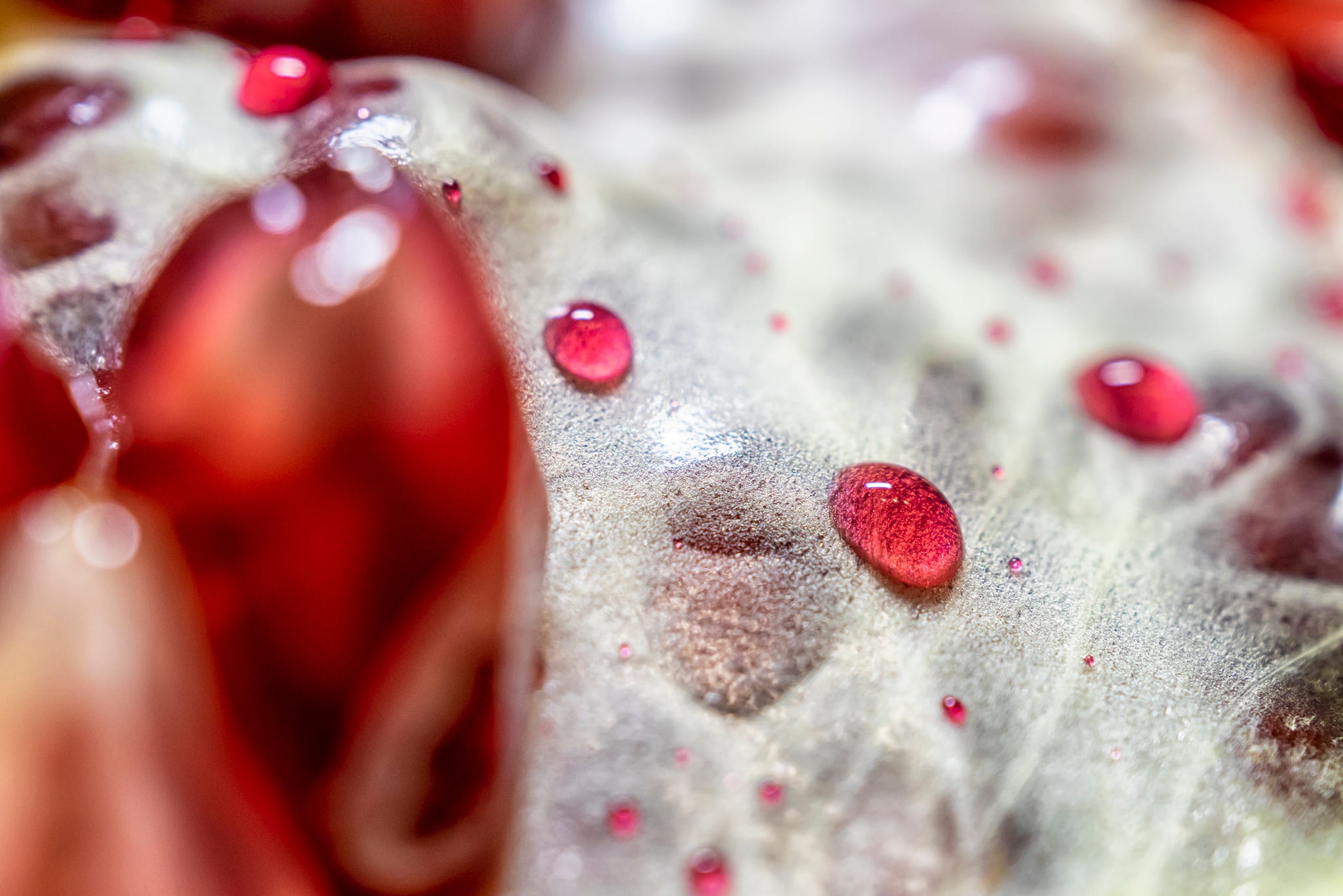 Sprinkle the pomegranate juice on the peeled pomegranate to form red water droplets.  Abstract red and yellow background.