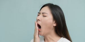woman yawning against blue background