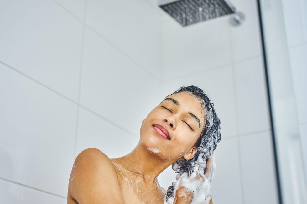 shot of an attractive young woman washing her hair with shampoo in the shower at home