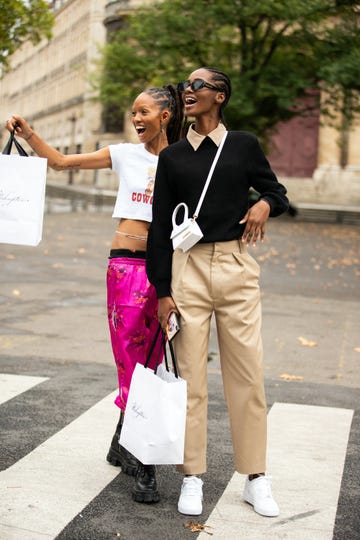 two individuals crossing a street while holding shopping bags