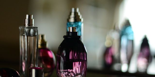 four perfume bottles on a black table by a framed antique mirror