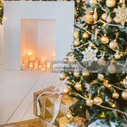 christmas living room decoration, white and gold colors interior decoration background, xmas home decoration with presents, christmas lights, firepit and tree indoors