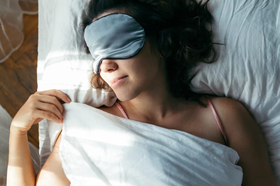 woman sleeping in mask in bed bright light on face morning time