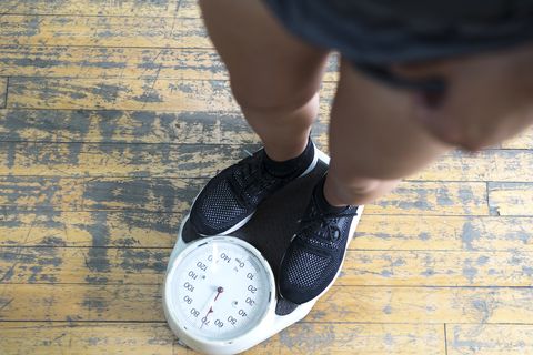 low section of man checking weight on scale in gym men's health