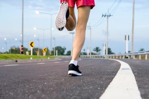 vrouw aan het hardlopen op asfalt weg in zwarte hardloopschoenen met witte sokken en roze sportbroekje