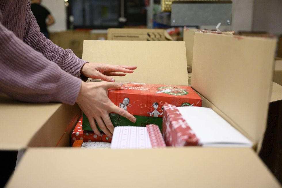 04 december 2019, berlin in the christmas workshop of the christian aid organization samaritans purse, a helper puts a gift box in a cardboard box on the occasion of the gift campaign christmas in a shoebox people from germany can pack presents in a shoebox and give them to needy children from eastern europe photo lisa ducretdpa photo by lisa ducretpicture alliance via getty images