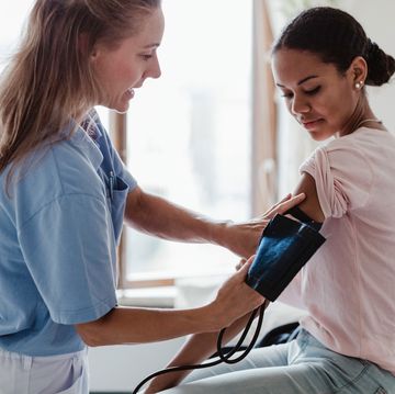 vrouw doet een bloeddrukband om de arm van een andere vrouw