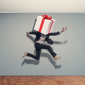 businessman jumps with a large gift package in front of his facedigital composite