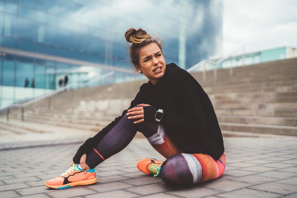 woman with pain in the leg during workout sitting on ground