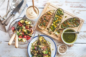 a colourful and fresh spread of grilled eggplantaubergine with salad, herb butter and mashed butter beans a balanced and healthy meal for vegans, vegetarians or vegetable lovers