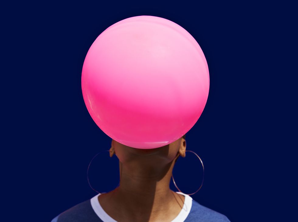 obscured face of woman blowing balloon against blue background