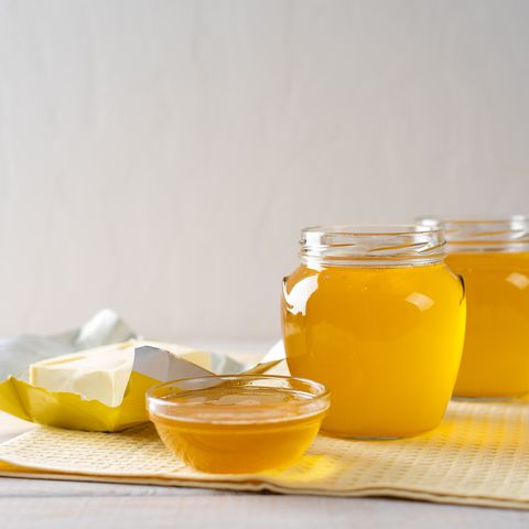 Hot homemade ghee butter in glass jars on a light background.