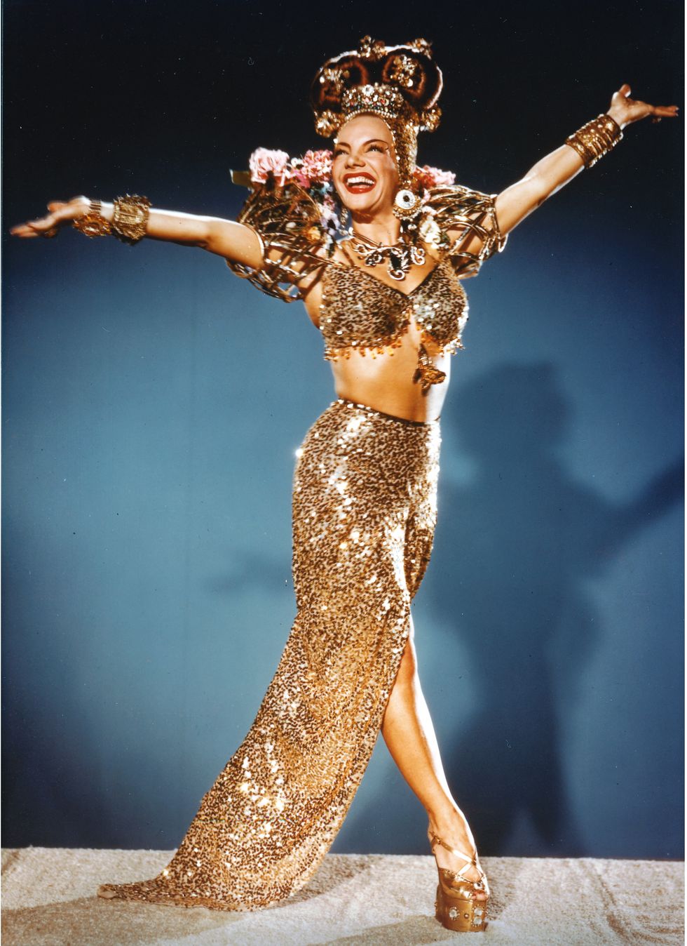 carmen miranda 1909 1955, portuguese born brazilian singer, actress and dancer, wearing a long gold sequuinned split skirt, with a matching bra top and various gold accoutrements, including a gold headdress, with her outstretched either side of her, circa 1950 photo by silver screen collectiongetty images