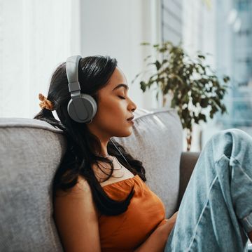 shot of a young woman using headphones while relaxing on the sofa at home