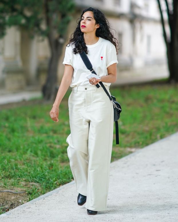 paris, france june 18 a guest wears earrings, a white ami top, white leather wide legs pants, a crossbody black bag, black boots, outside ami, during paris fashion week menswear springsummer 2020, on june 18, 2019 in paris, france photo by edward berthelotgetty images