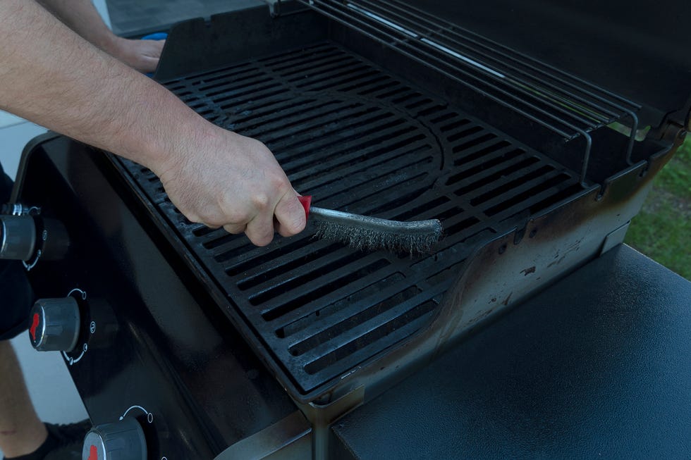 a man brushes an street black grill with an iron brush grill preparation for frying meat