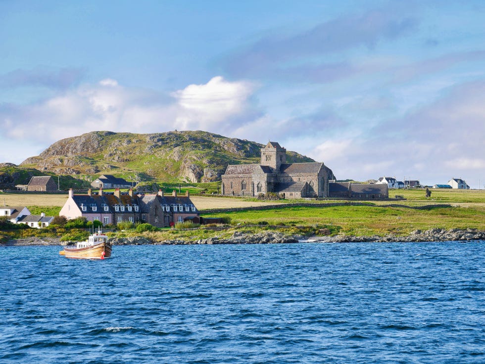 iona abbey, cottages and a fishing boat on a sunny day in autumn from the sound of iona.