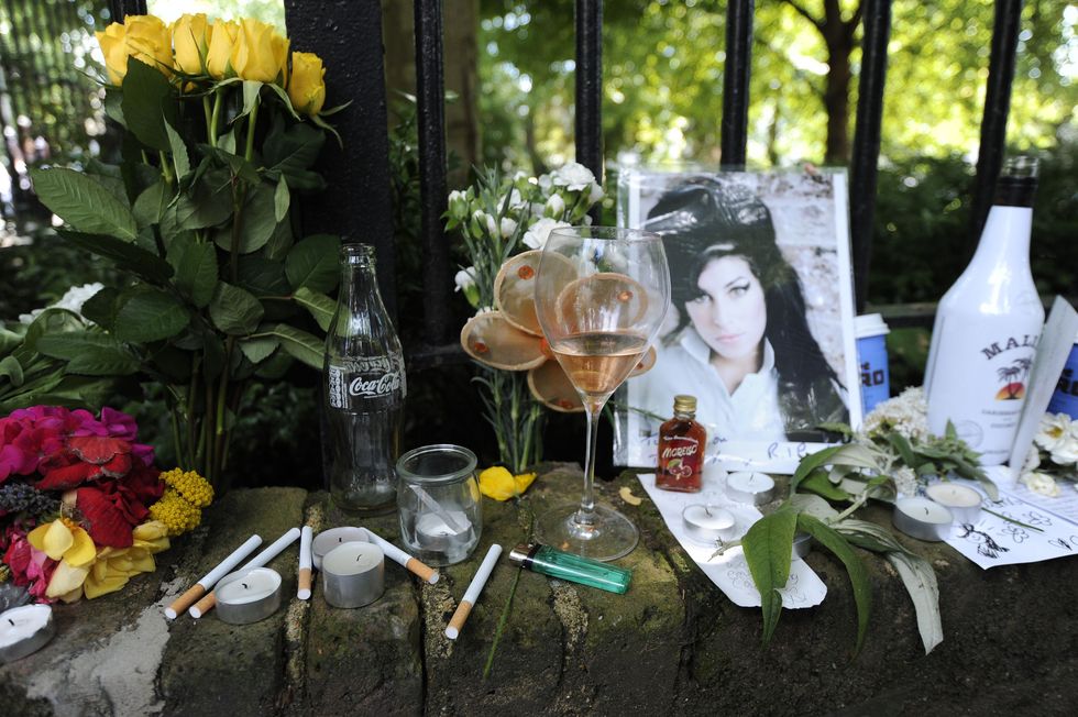 Cigarettes, alcohol and photos are left with flowers and messages on July 24, 2011, near the house in north London where the body of Amy Winehouse was found the previous day