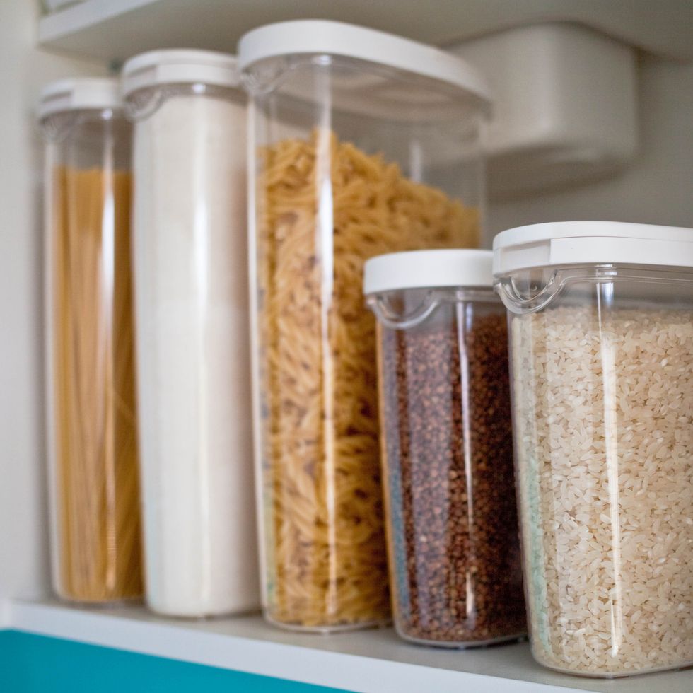 Stocked kitchen pantry with food - pasta, buckwheat, rice and sugar . The organization and storage in kitchen of a case with grain in plastic containers.