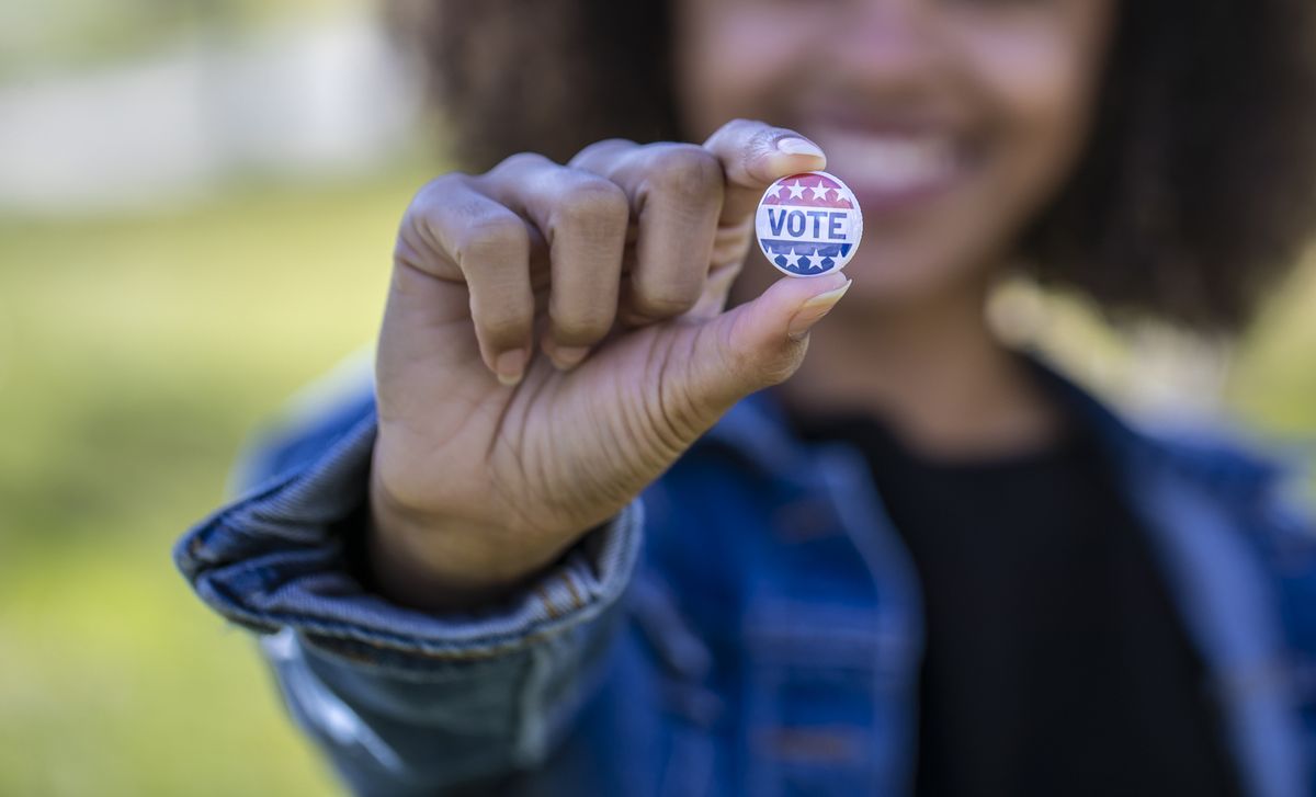 a young african american woman holding a voting badge
