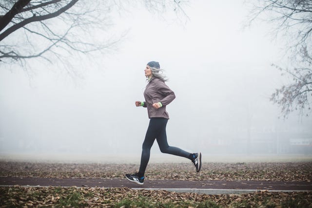 gray hair women running outdoor in park she is wearing sports clothing fogy and cold weather