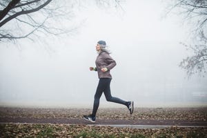 gray hair women running outdoor in park she is wearing sports clothing fogy and cold weather