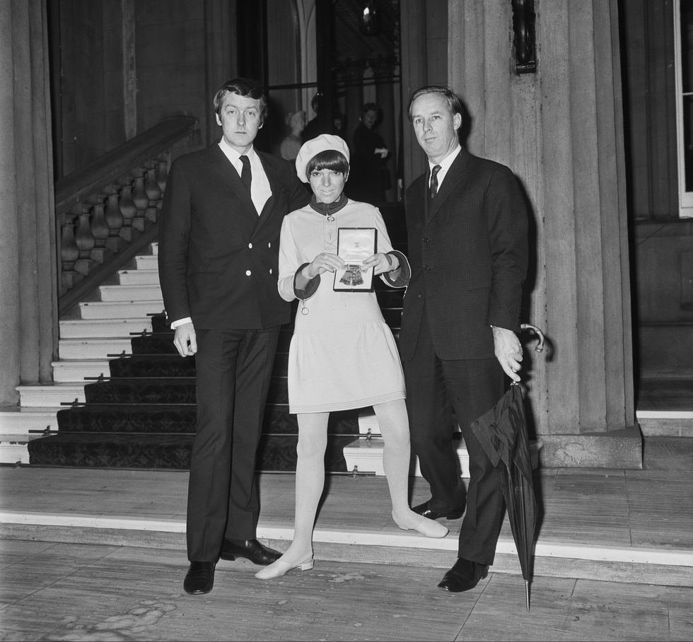 english fashion designer and fashion icon mary quant, wearing wool jersey mini skirted dress and beret, holds her obe with her business partner and husband, british entrepreneur alexander plunket greene 1932 1990, and the chairman of mary quant fashion brand, british entrepreneur archie mcnair 1919 2015, at buckingham palace, london, uk, 15th november 1966 photo by central presshulton archivegetty images