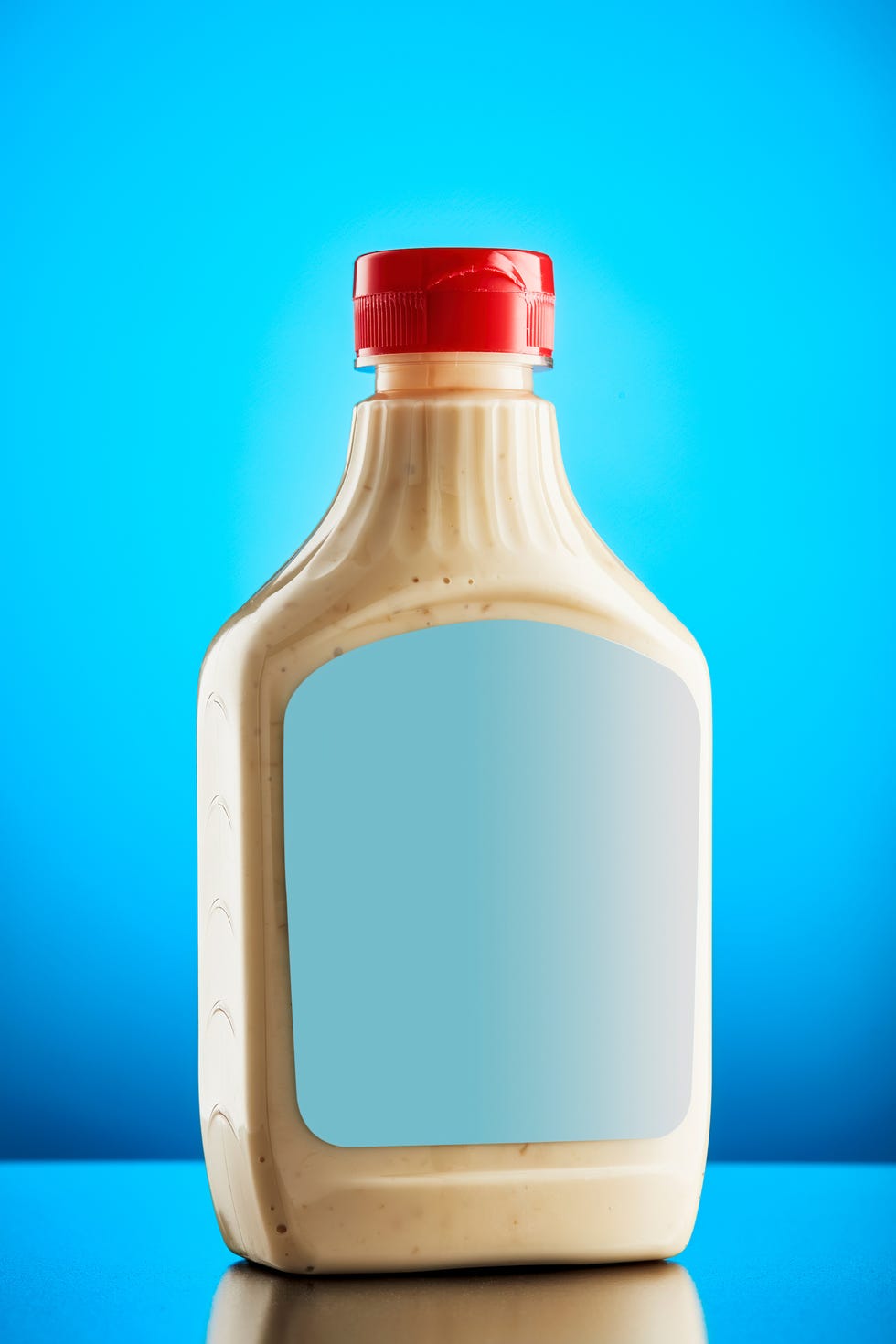 horseradish mustard sauce in plastic bottle with blank label against blue background