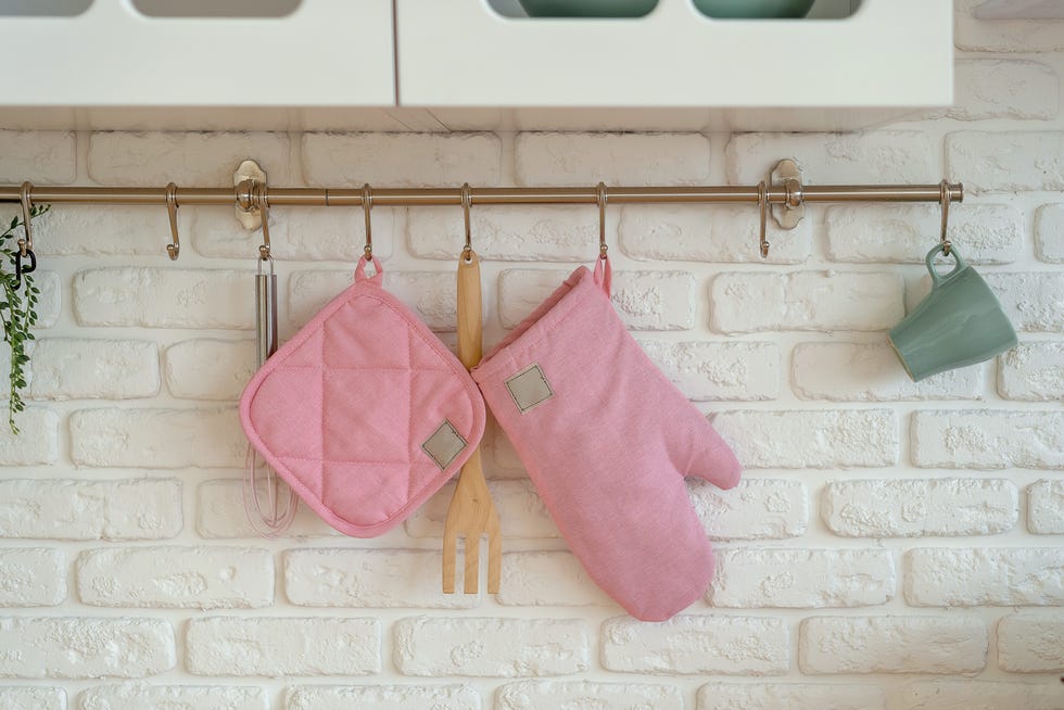 kitchen glove, potholder, oven protection are hanging over white brick wall. safety cooking concept. copy space.