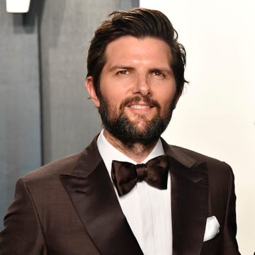 adam scott smiles at the camera while wearing a brown tuxedo and bowtie with a white shirt and pocket square, photo by frazer harrisongetty images