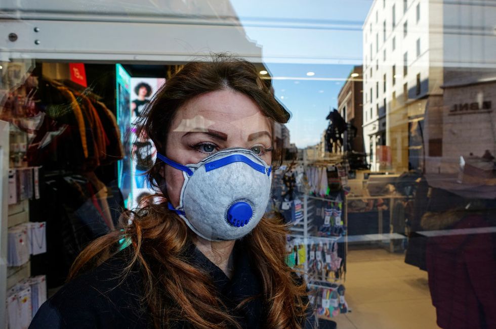 A woman while looking out of a shop, wears an antivirus