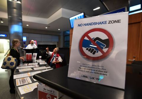 a traveller has questions answered at an information booth beside a reminder not to shake hands over coronavirus concerns at los angeles international airport on march 12, 2020 one day before a us flight travel ban hits 26 european countries amid ongoing precautions over the coronavirus   us president donald trump announced a shock 30 day ban on travel from mainland europe over the coronavirus pandemic that has sparked unprecedented lockdowns, widespread panic and another financial market meltdown thursdaythe announcement came as china, where the outbreak that first emerged in december, showed a dramatic drop in new cases and claimed the peak of the epidemic had passed photo by frederic j brown  afp photo by frederic j brownafp via getty images