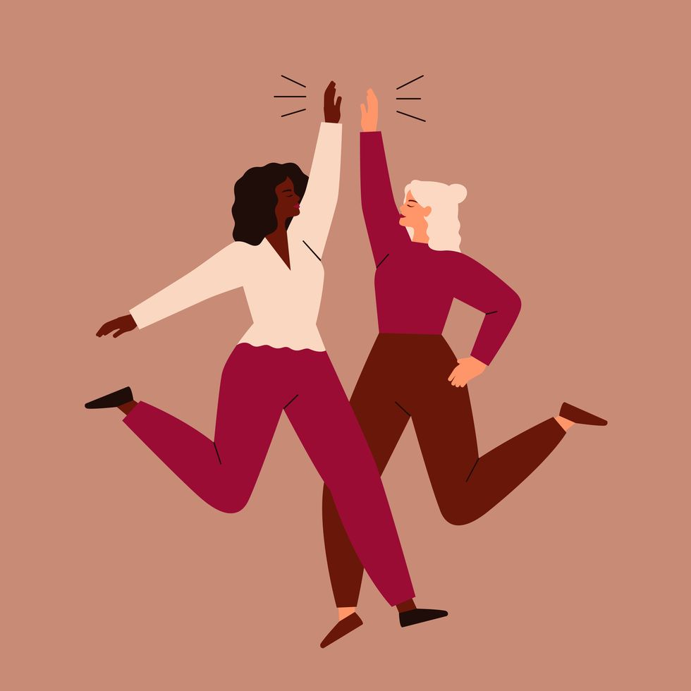 two women jump and high five each other friendship and teamwork of girls vector concept of the females empowerment movement