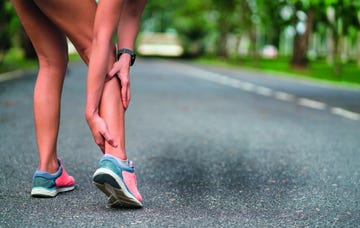 achilles injury on running outdoors. women holding achilles tendon by hands close up and suffering with pain. ankle twist sprain accident in sport exercise running jogging.