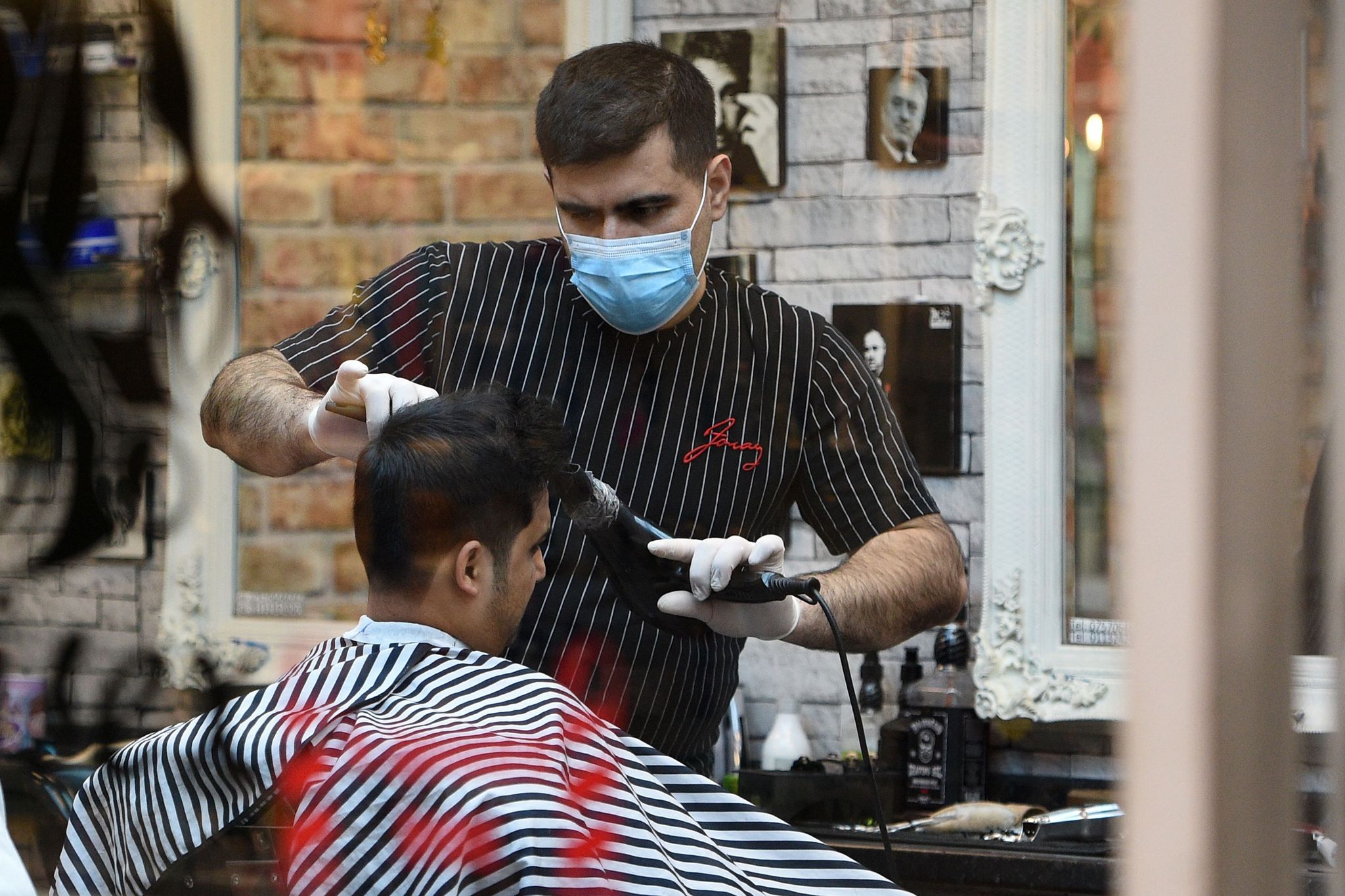 a barber wears a protective face mask as he cuts the hair of a customer in central leeds, northern england on the morning of march 21, 2020, a day after the british government said it would help cover the wages of people hit by the coronavirus outbreak as it tightened restrictions to curb the spread of the disease photo by oli scarff  afp photo by oli scarffafp via getty images