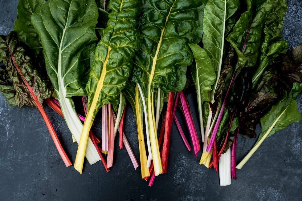 Fresh Swiss chard leaves with colorful stems arranged on a dark surface