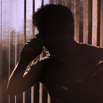 silhouette of an unknown man on a phone against window blinds conceptual with space for copy