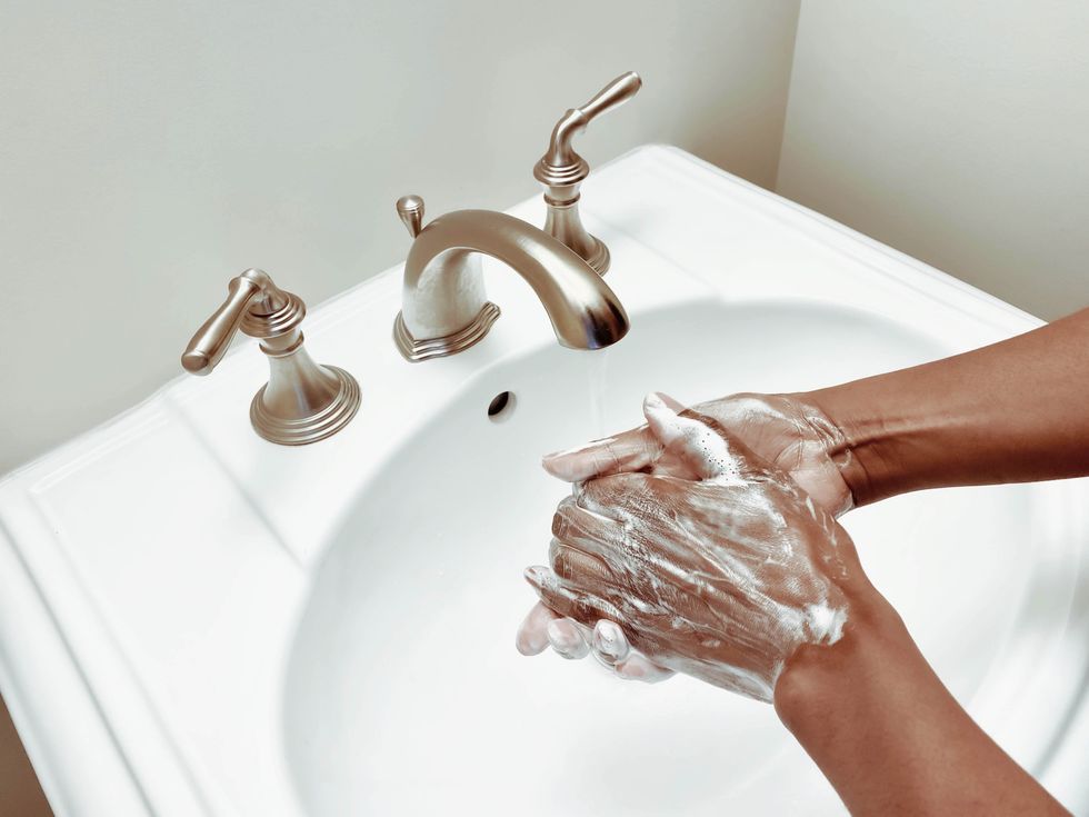 woman lathers on the soap to wash hands in powder room sink