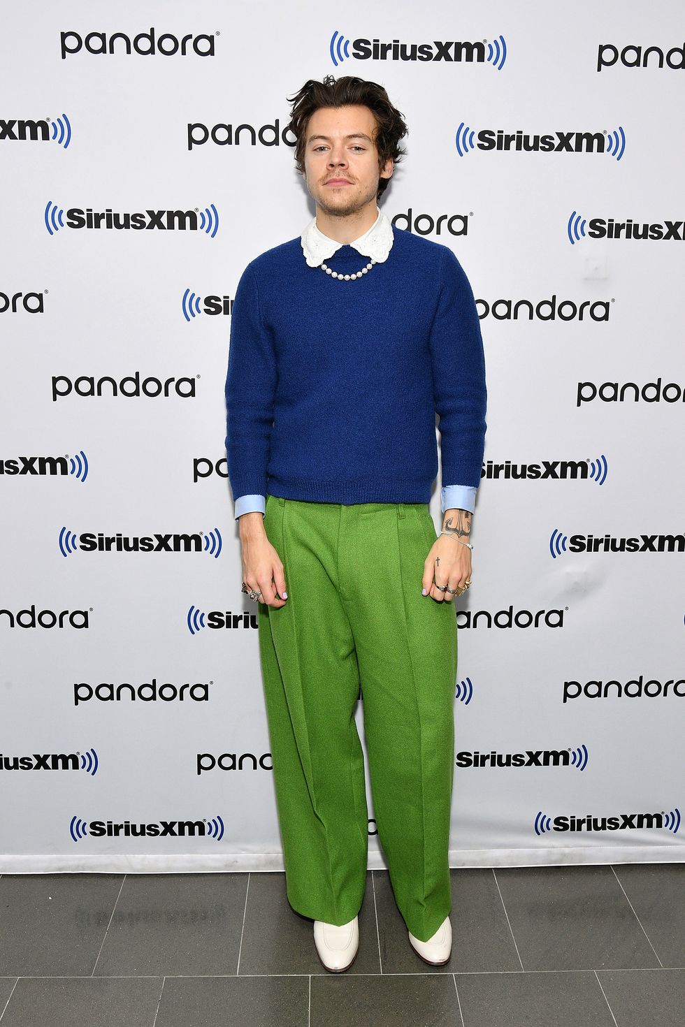 harry styles wearing a blue jumper and green trousers
