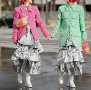 Silver Dresses Street Style two women photographed on the street holding hands in pastel coats, silver dresses, and white boots