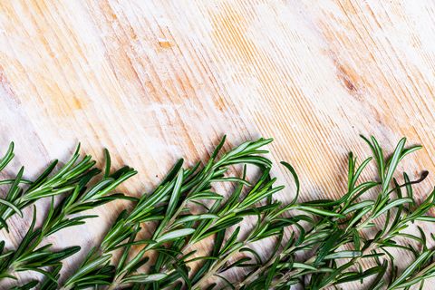 green sprigs of rosemary on wooden surface