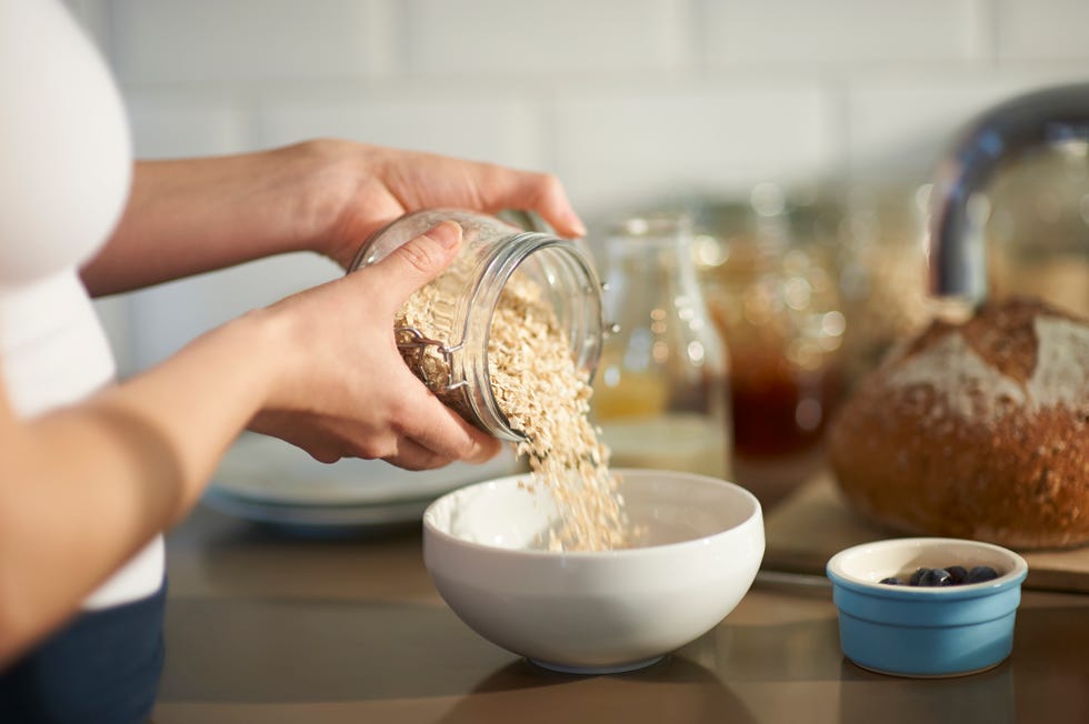 close up of a woman preparing a wholesome breakfast by pouring oats into a bowl from a plastic free jar with fresh berries